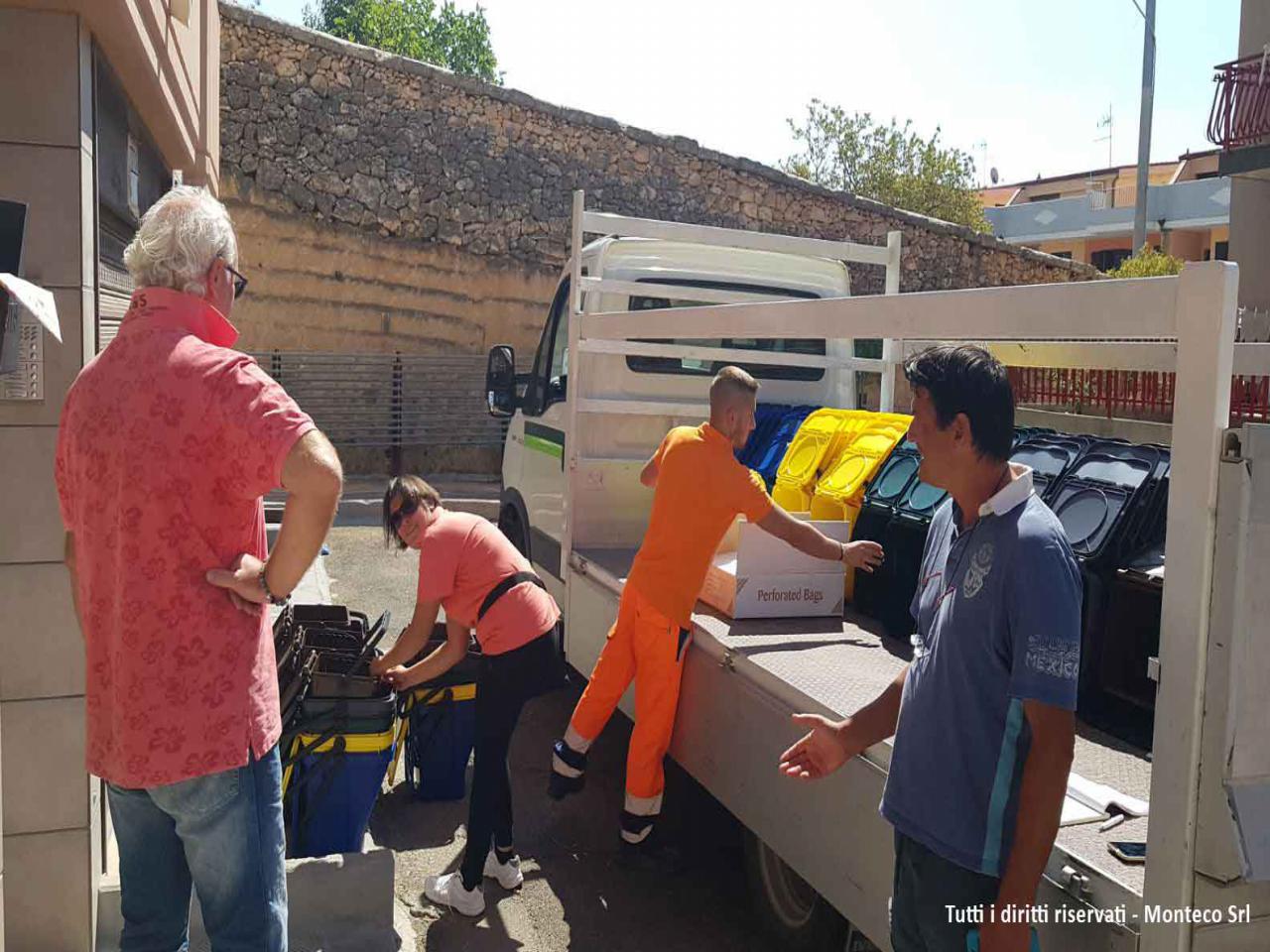 operatori ecologici caricano bidoni differenziata su camion