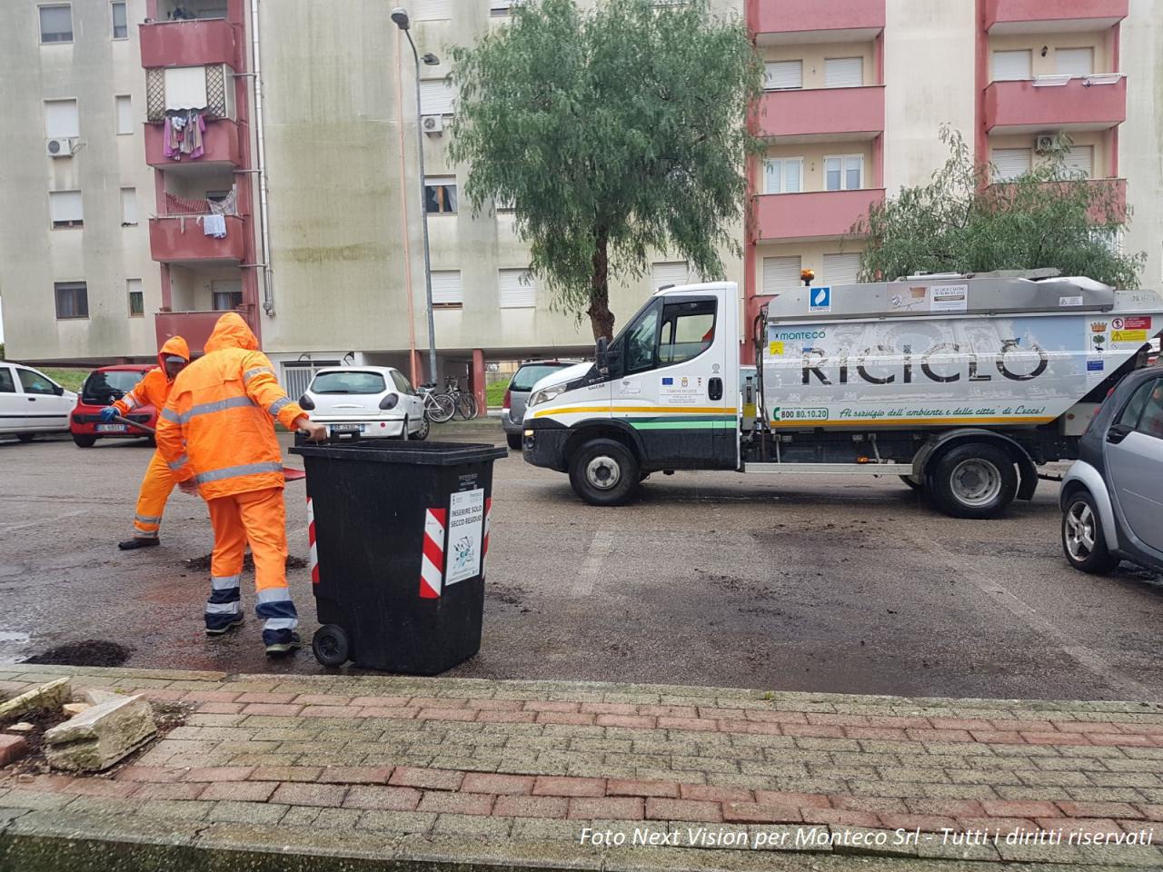 operatori ecologici che spostano il bidone della spazzatura