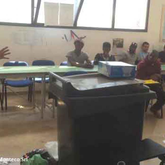 bidone dei rifiuti, uomini seduti ai banchi di scuola